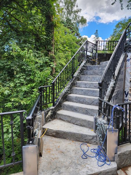 Stone staircase leading upwards, bordered by greenery and a blue sky