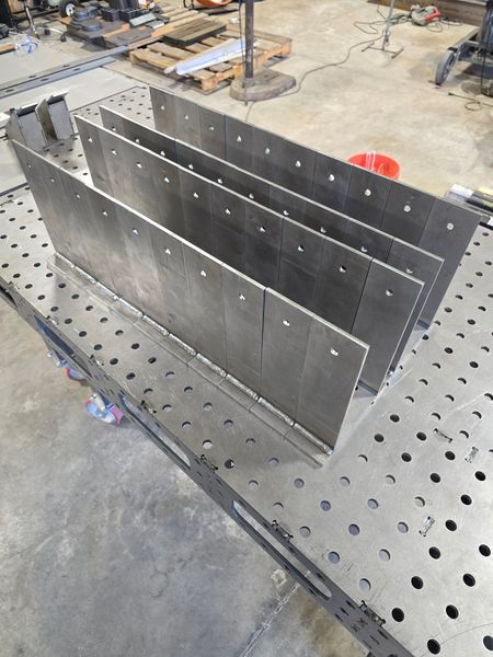 Metal fabrication in progress, showcasing neatly arranged stainless steel plates with holes